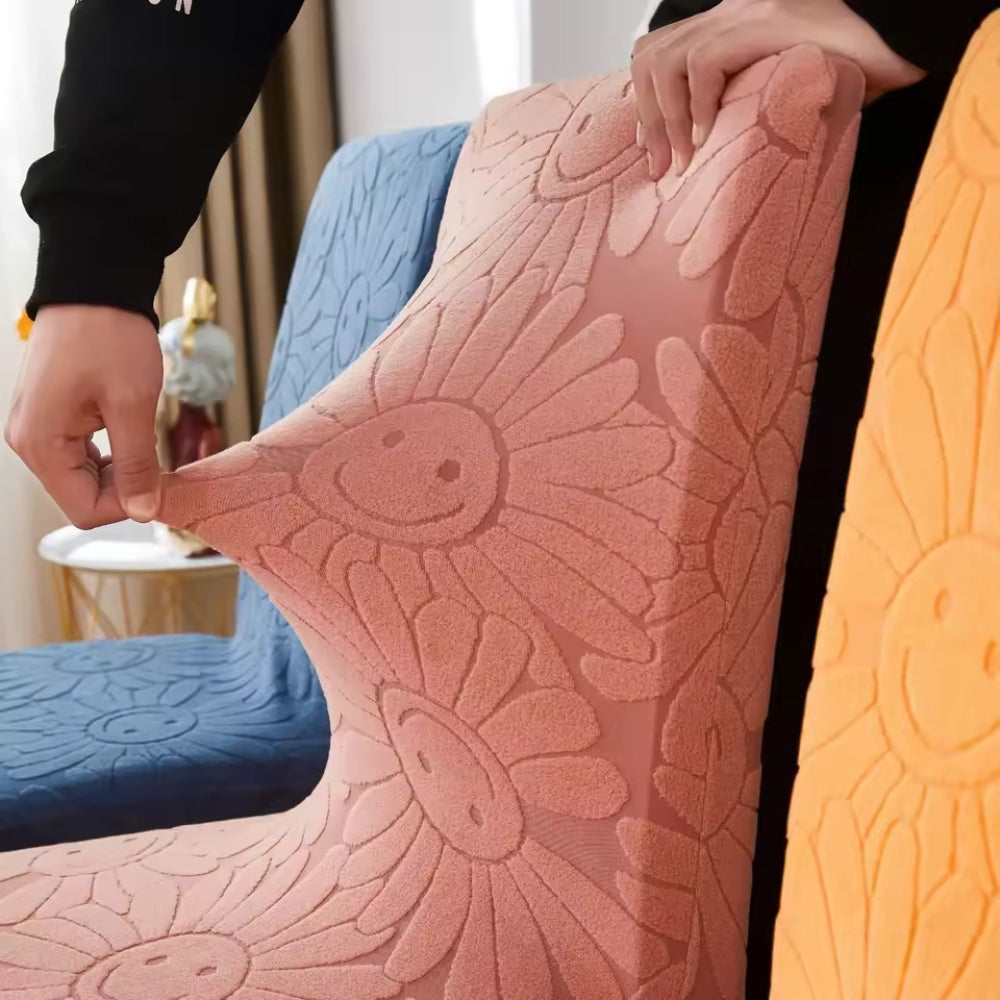 Close-up of hands stretching the Rosy Blush stretch chair cover, demonstrating the elastic fit and floral fabric with smiling daisy pattern.