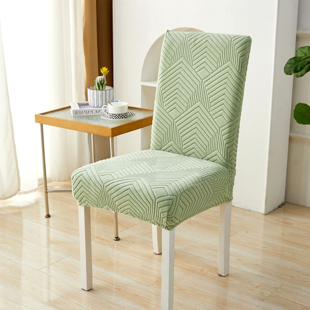Funda de silla elástica jacquard Velvet Haven en verde salvia con patrón Chevron Maze sobre una silla de comedor blanca. La funda ofrece ajuste elástico y diseño moderno, ideal para proteger muebles y decorar el hogar.