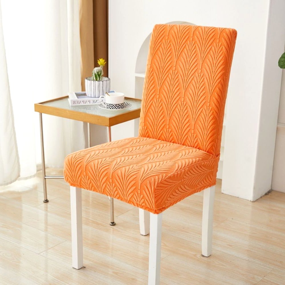 Funda elástica de jacquard Velvet Haven para silla, color naranja atardecer, con patrón de palma tejida, mostrada en una silla de comedor, destacando su ajuste elástico. Añade un toque tropical moderno a la decoración del hogar.