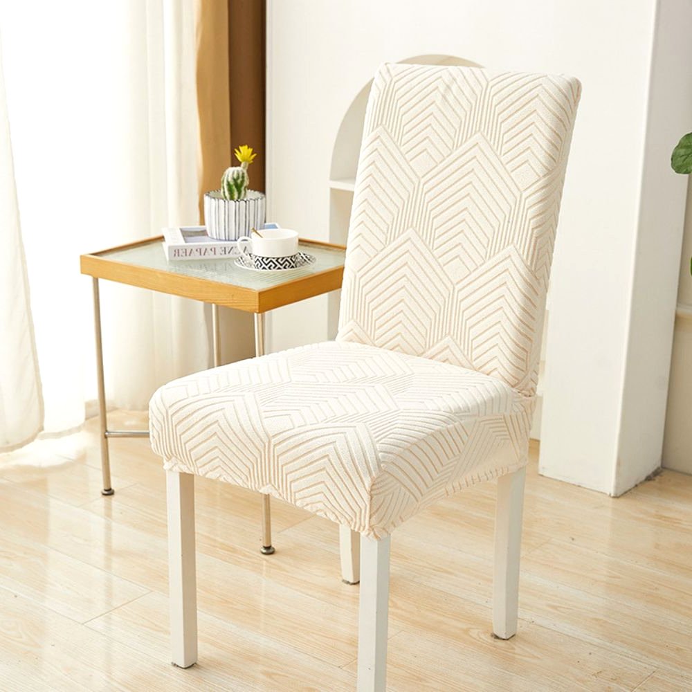 Funda de silla elástica jacquard Velvet Haven en beige cálido con patrón Chevron Maze sobre una silla de comedor blanca. La funda ofrece ajuste elástico y diseño moderno, ideal para proteger muebles y decorar el hogar.
