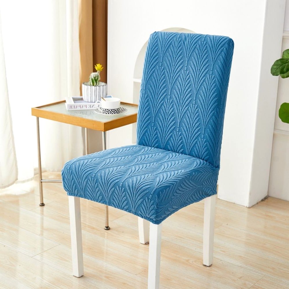 Velvet Haven elastischer Jacquard-Stuhlbezug in Ozeanblau mit Palmenwebemuster, gezeigt auf einem weißen Esszimmerstuhl. Dieser dehnbare Möbelschoner bietet modernes Design und einfache Montage.
