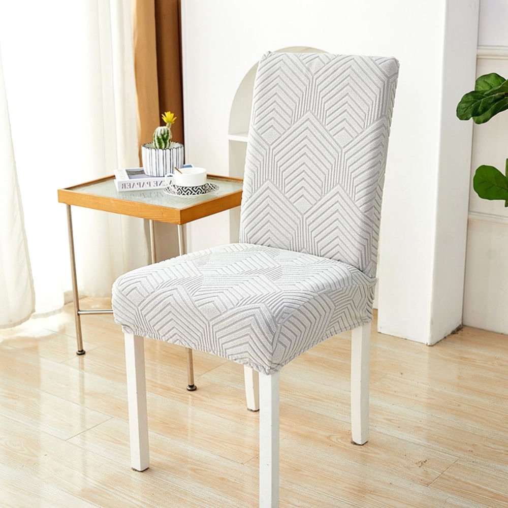 Ein weicher weißer Velvet Haven Stretch-Jacquard-Stuhlbezug mit Chevron-Maze-Muster auf einem weißen Esszimmerstuhl. Der Bezug bietet eine dehnbare Passform und modernes Design, geeignet für Möbelschutz und Wohndekoration.