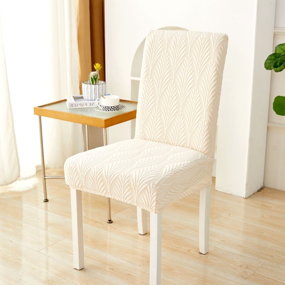 Velvet Haven elastischer Jacquard-Stuhlbezug in Warmbeige mit Palmenwebemuster, gezeigt auf einem weißen Esszimmerstuhl. Dieser dehnbare Möbelschoner bietet modernes Design und einfache Montage.